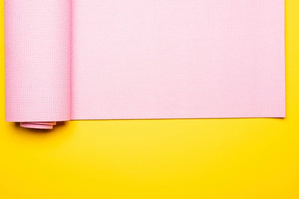 Vista superior do tapete de fitness rosa no fundo amarelo — Fotografia de Stock