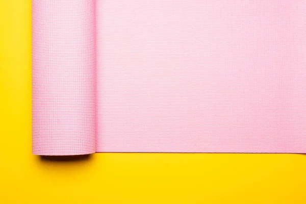 Top view of pink fitness mat on yellow background — Stock Photo