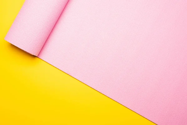 Top view of pink fitness mat on yellow background — Stock Photo