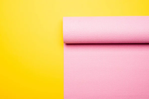 Top view of pink fitness mat on yellow background — Stock Photo