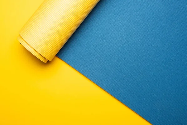 Vista superior de la alfombra de fitness azul sobre fondo amarillo - foto de stock