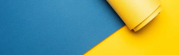 Vista superior do tapete de fitness azul no fundo amarelo, tiro panorâmico — Fotografia de Stock