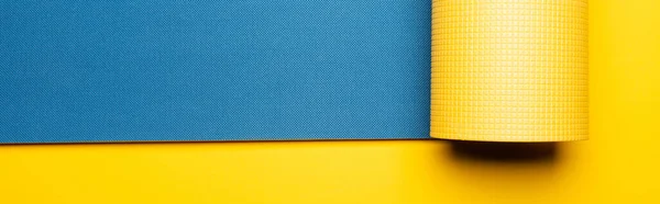 Top view of blue fitness mat on yellow background, panoramic shot — Stock Photo