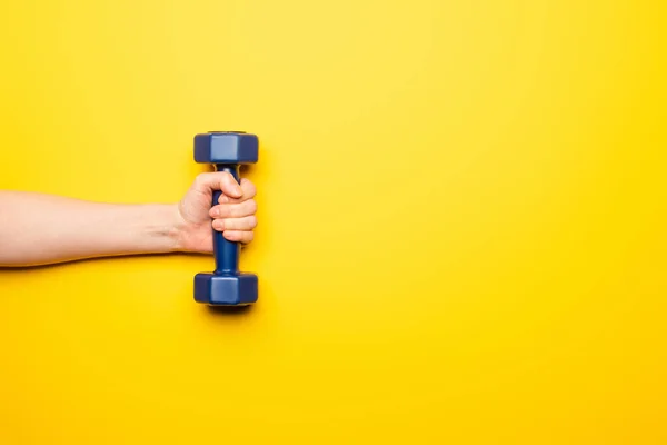 Vista ritagliata della donna che tiene il manubrio blu su sfondo giallo — Foto stock