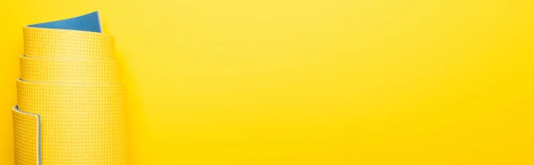 Вид сверху на катаный фитнес мат на желтом фоне, панорамный снимок — стоковое фото