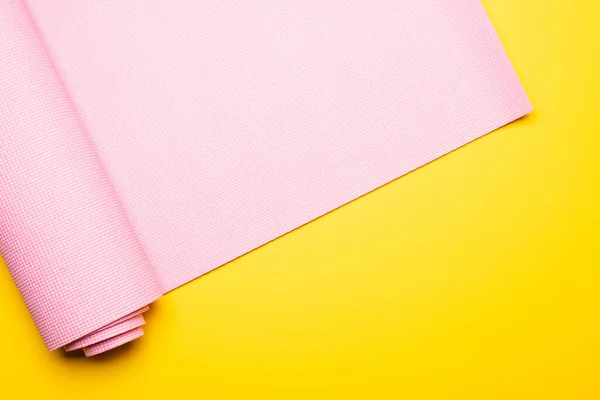 Vue de dessus du tapis de fitness rose sur fond jaune — Photo de stock