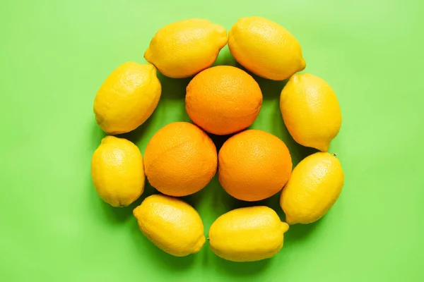 Top view of ripe lemons and oranges arranged in circle on green background — Stock Photo