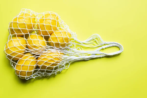 Vista superior de limões inteiros maduros em saco de cordas no fundo amarelo — Fotografia de Stock