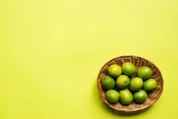 Vista dall'alto di lime mature in cesto di vimini su sfondo colorato — Foto stock