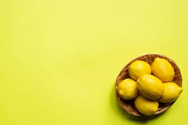 Von oben Ansicht der reifen Zitronen in Weidenkorb auf buntem Hintergrund — Stockfoto