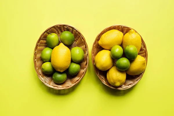 Draufsicht auf reife Limetten und Zitronen in Weidenkörben auf buntem Hintergrund — Stockfoto