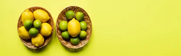 Верхний вид спелых лаймов и лимонов в плетеных корзинах на красочном фоне, панорамный урожай — стоковое фото