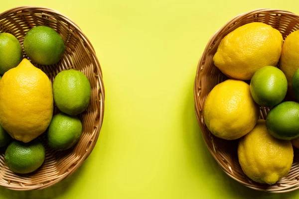 Draufsicht auf reife Limetten und Zitronen in Weidenkörben auf buntem Hintergrund — Stockfoto