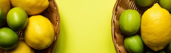 Top view of ripe limes and lemons in wicker baskets on colorful background, panoramic crop — Stock Photo