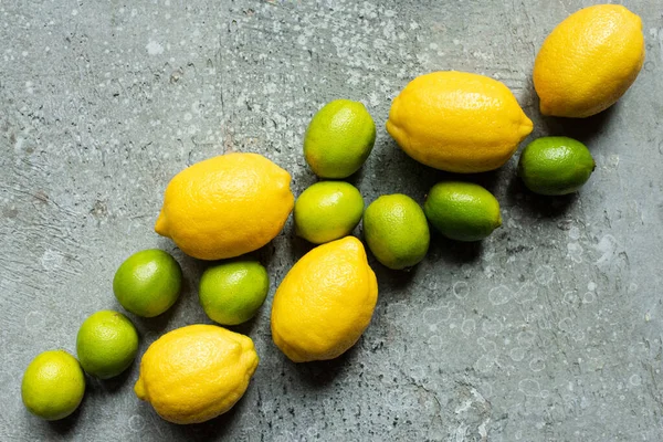 Вид зверху на стиглі жовті лимони і зелені межі на бетонній текстурованій поверхні — стокове фото