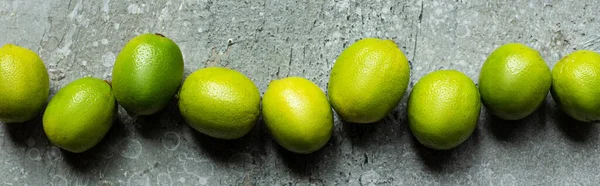 Top view of ripe green limes on concrete textured surface, panoramic crop — Stock Photo