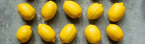 Pose plate avec des citrons jaunes mûrs sur surface texturée en béton, culture panoramique — Photo de stock