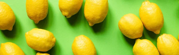 Vista superior de limones amarillos maduros dispersos sobre fondo verde, cultivo panorámico - foto de stock