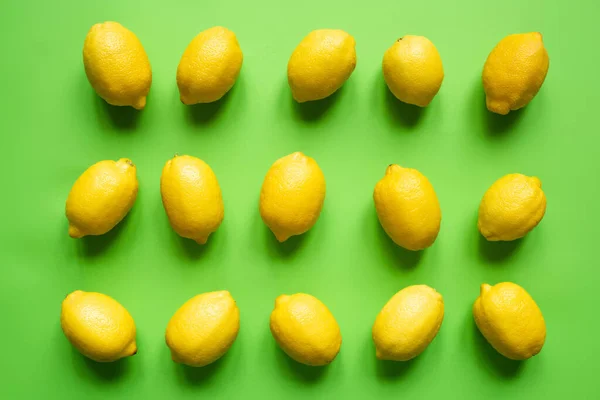 Flat lay with ripe yellow lemons on green background — Stock Photo
