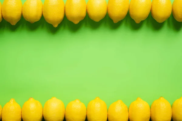 Vista superior de limones amarillos maduros sobre fondo verde con espacio de copia - foto de stock