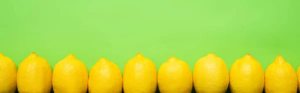 Top view of ripe yellow lemons on green background with copy space, panoramic crop — Stock Photo