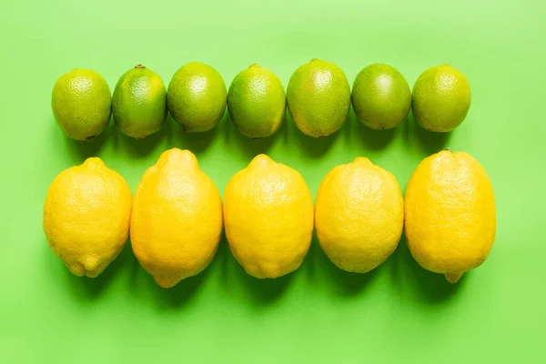 Flat lay with ripe lemons and limes on green background — Stock Photo