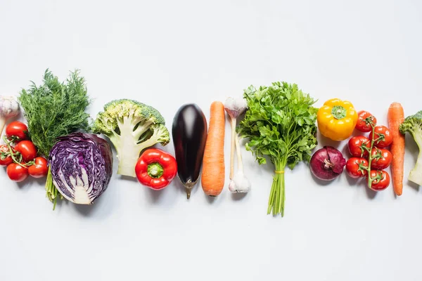 Вид зверху барвистих різноманітних свіжих овочів у лінії на білому тлі — стокове фото