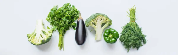 Flat lay with assorted green vegetables and eggplant on white background, panoramic shot — Stock Photo