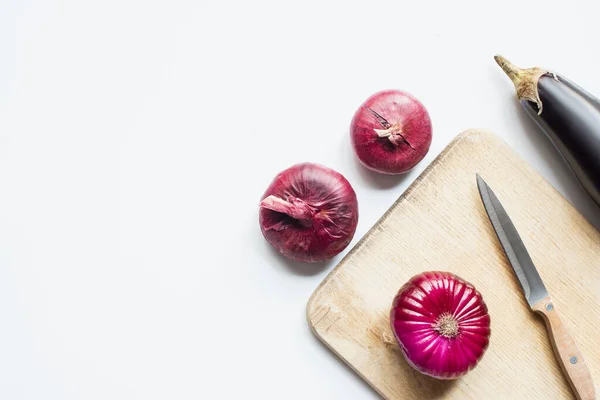 Top view of purple whole vegetables, knife and wooden cutting board on white background — Stock Photo