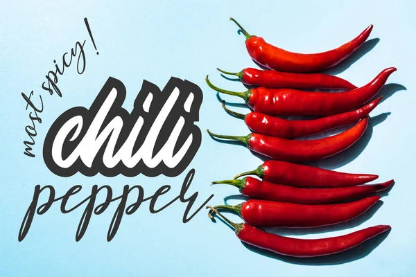 Top view of red peppers near most spicy lettering on blue surface — Stock Photo