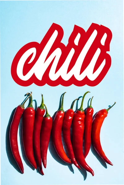 Top view of fresh and organic peppers near chili lettering on blue — Stock Photo