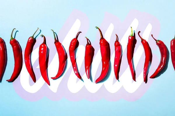 Top view of organic spicy peppers near chili lettering on blue — Stock Photo
