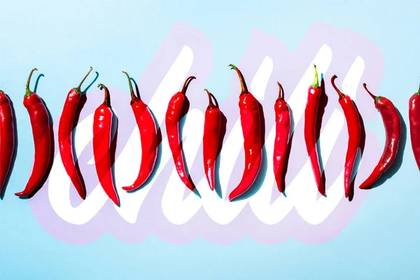 Vista dall'alto di peperoni piccanti biologici vicino a lettering peperoncino su blu — Foto stock