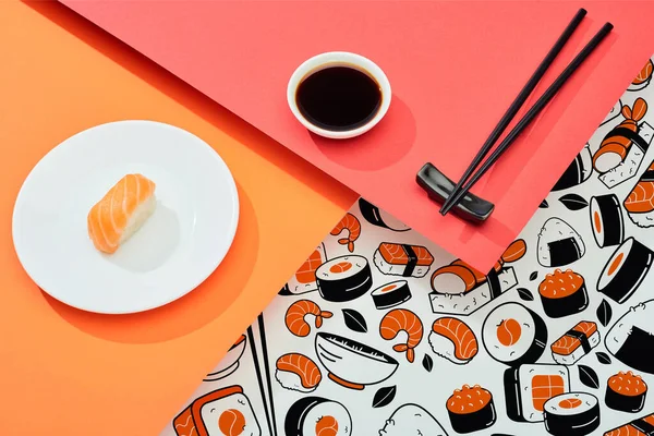 Fresh nigiri with salmon near soy sauce, chopsticks and sushi illustration on red, orange, white surface — Stock Photo