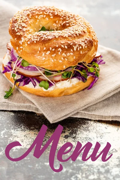 Fresh bagel on napkin near menu lettering on textured surface — Stock Photo