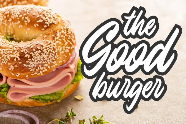 Delicioso bagel com presunto perto do bom hambúrguer lettering na superfície texturizada — Fotografia de Stock