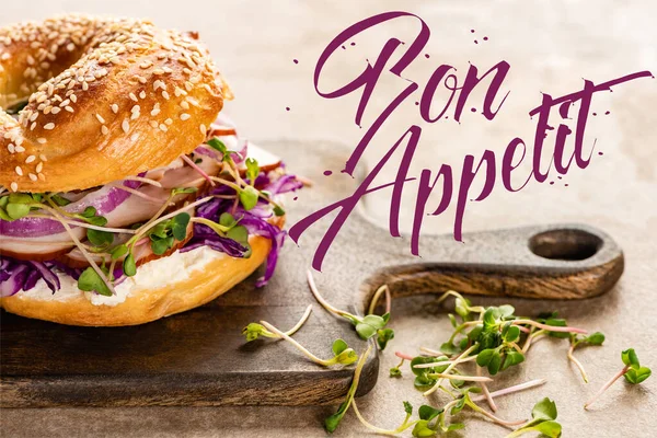 Frischer und köstlicher Bagel in der Nähe von leckerem Appetit-Schriftzug auf Holzschneidebrett — Stockfoto