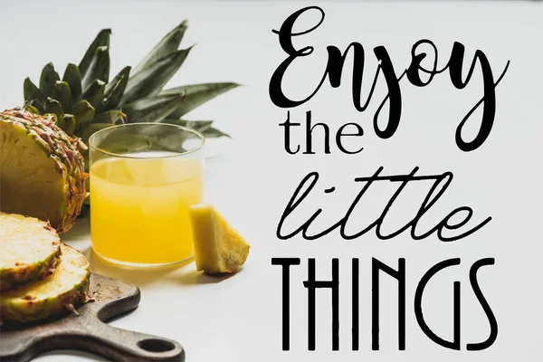 Fresh pineapple juice near sliced fruit on wooden cutting board and enjoy the little things lettering on white — Stock Photo