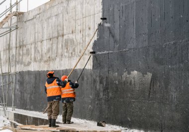 Sovetskaya Gavan, Rusya Federasyonu - 16 Ocak 2017: İki işçi, boya su geçirmez bir bina bir duvar boyası