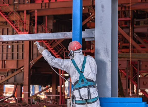 Worker paints a metal frame at construction site