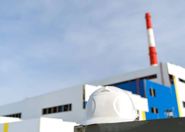 建設中の発電所を背景にしたホワイトエンジニアリングヘルメット — ストック写真