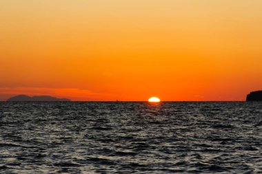 Güneş turuncu gökyüzü ile sahil kenarını gizliyor.