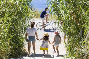 Genç mutlu beyaz aile açık havada bisiklet ve Maguelone, Fransa'da bir göl yakınında yürüyüş üç çocuk