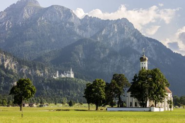 Schwangau, Almanya. Dünya ünlü Schloss Neuschwanstein Şatosu arka planda St. Coloman kiliseyle görünümünü doğal uzun atış