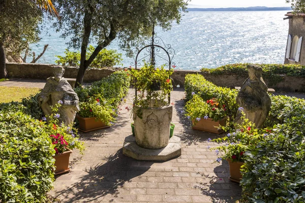 Garden with a well and two statues in Sirmione, northern Italy, with views to Lake Garda