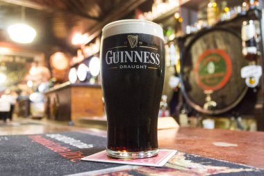 A pint of Irish dry stout Guinness over the counter of The House of McDonnell, a traditional pub in Ballycastle, County Antrim, Northern Ireland clipart