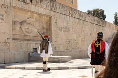 Atina, Yunanistan. Geleneksel üniformalı iki Evzone muhafızıyla birlikte Syntagma Meydanı 'ndaki Meçhul Asker' in mezarı, ziyaretçi kalabalığı tarafından izleniyor.
