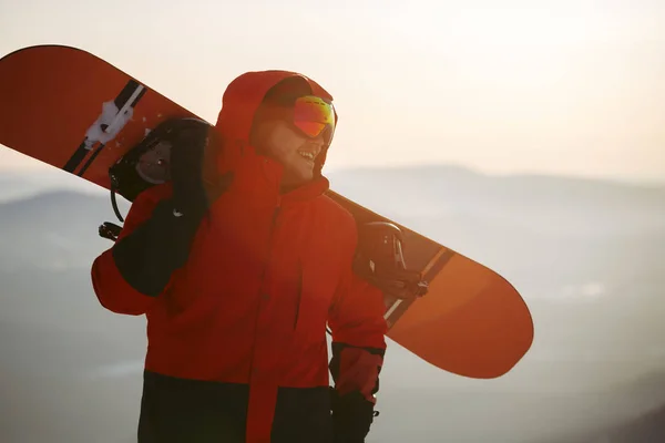 Um jovem no fundo do céu do pôr do sol com um snowboard — Fotografia de Stock