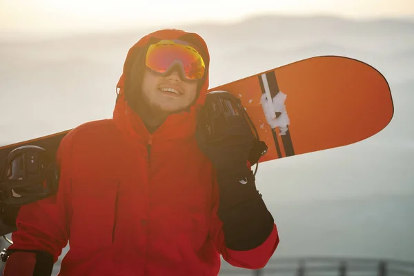 Um jovem no fundo do céu do pôr do sol com um snowboard — Fotografia de Stock