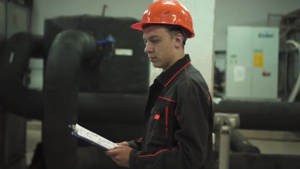 Un joven ingeniero está en una sala técnica. en la fábrica — Vídeos de Stock